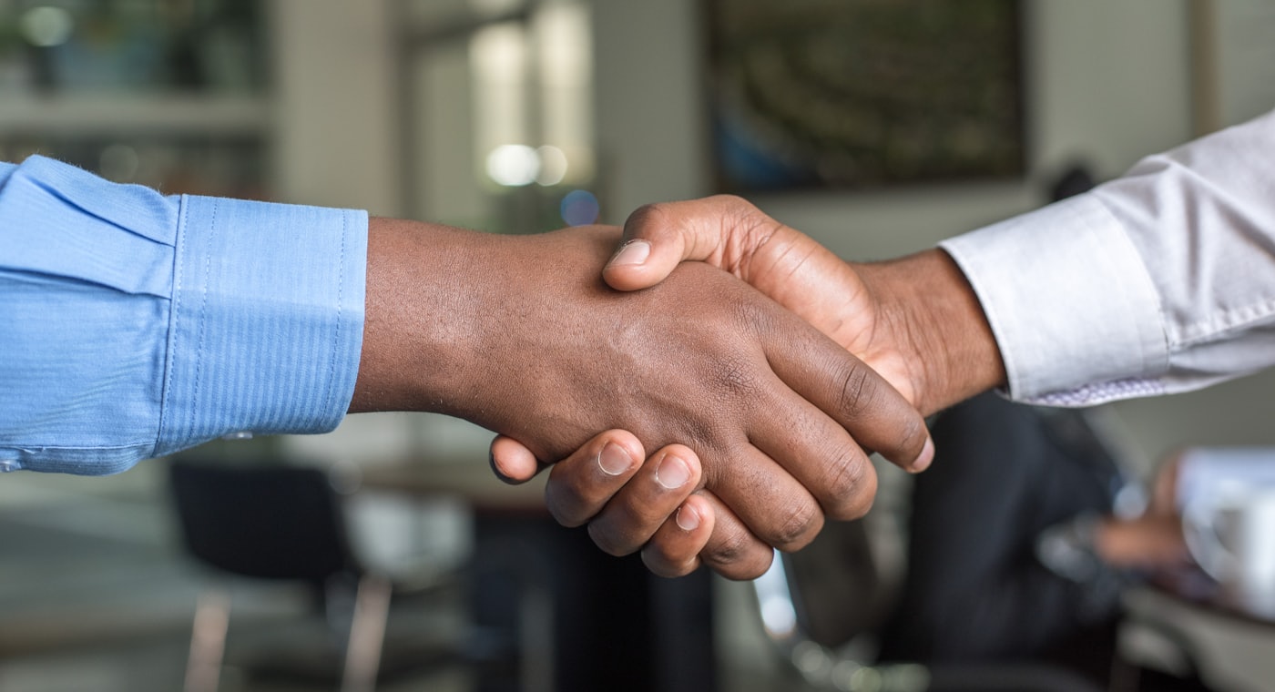 Aperto de mãos entre consultora e cliente selando um relacionamento comercial